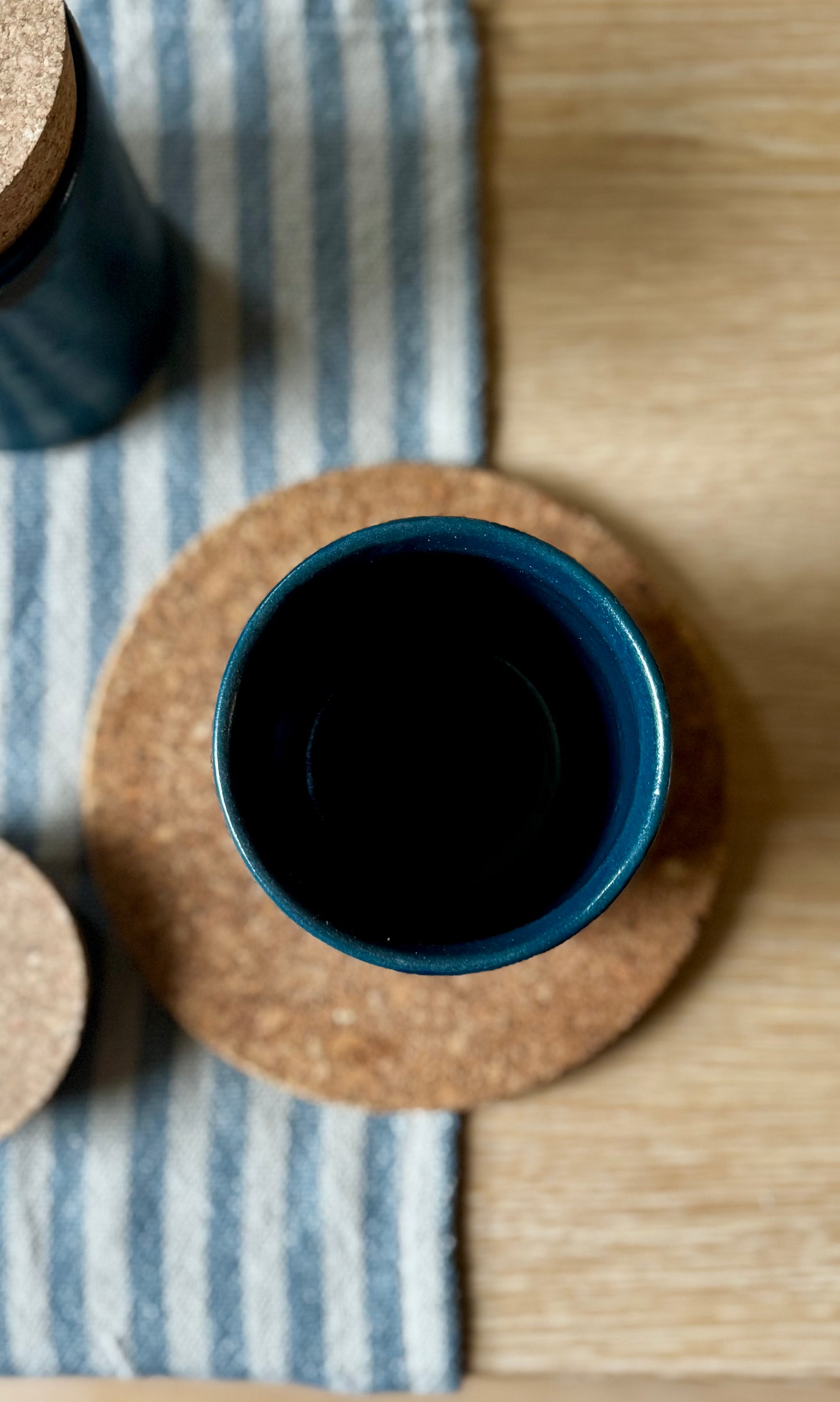 Blue ceramic container on a cork coaster with a striped cloth underneath