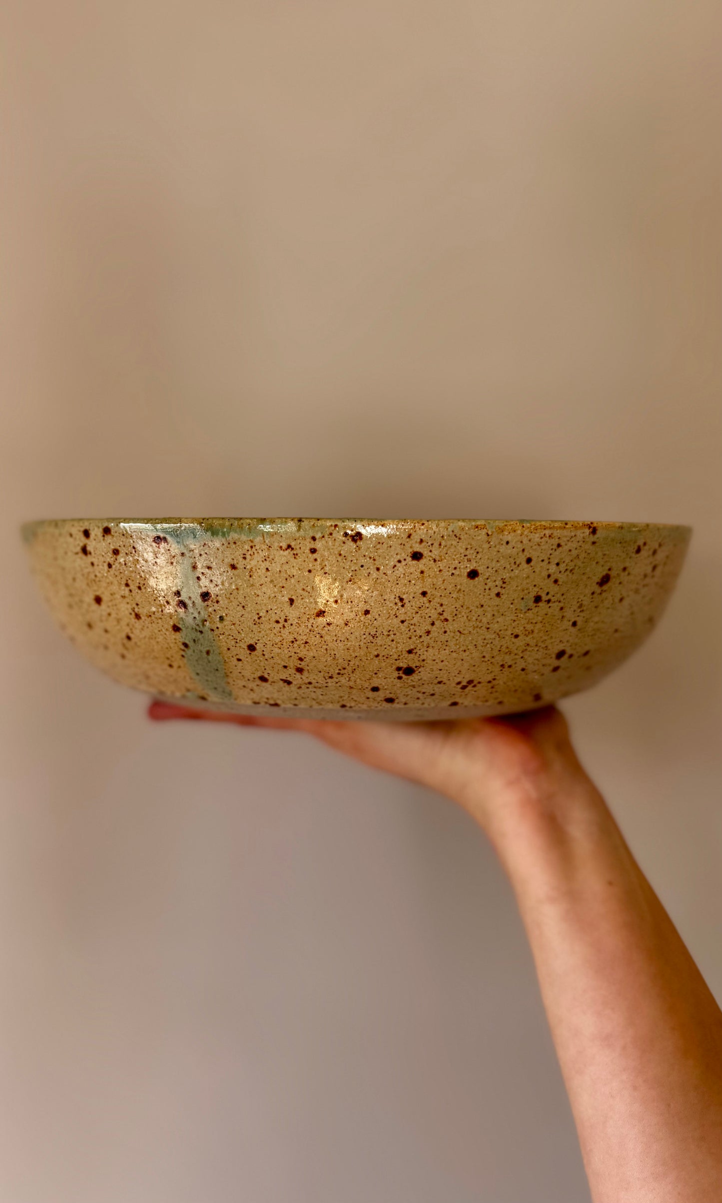 Handmade ceramic feasting bowl in celadon green from Herridge Potter - held side