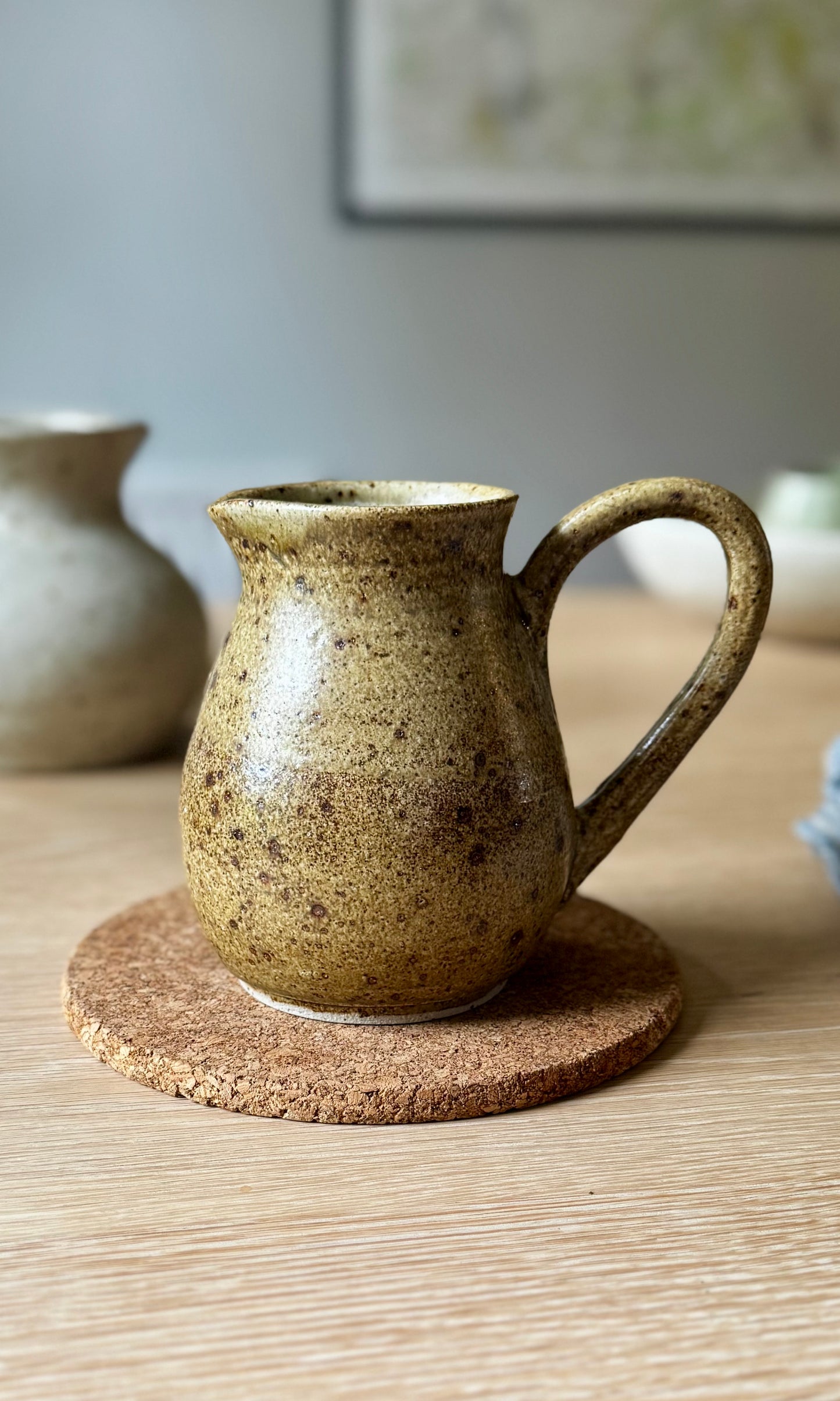 Brown ceramic pitcher on a cork coaster with a blurred background