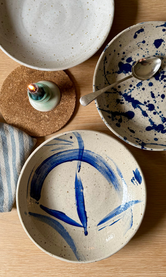 Ceramic bowls with blue abstract designs on a wooden surface.