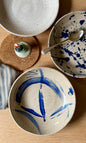 Ceramic bowls with blue abstract designs on a wooden surface.