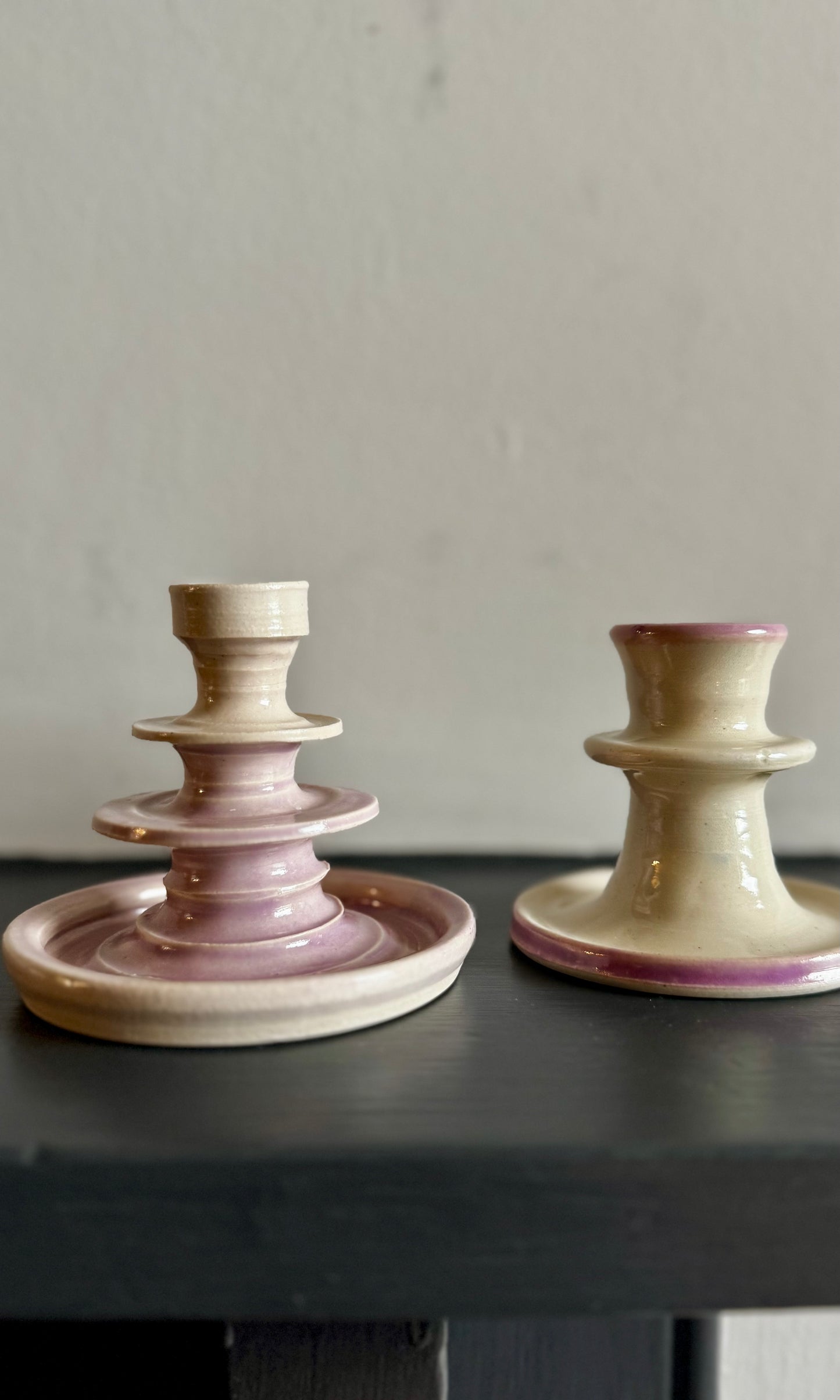 Two ceramic candle holders with a lilac and white design on a dark surface.