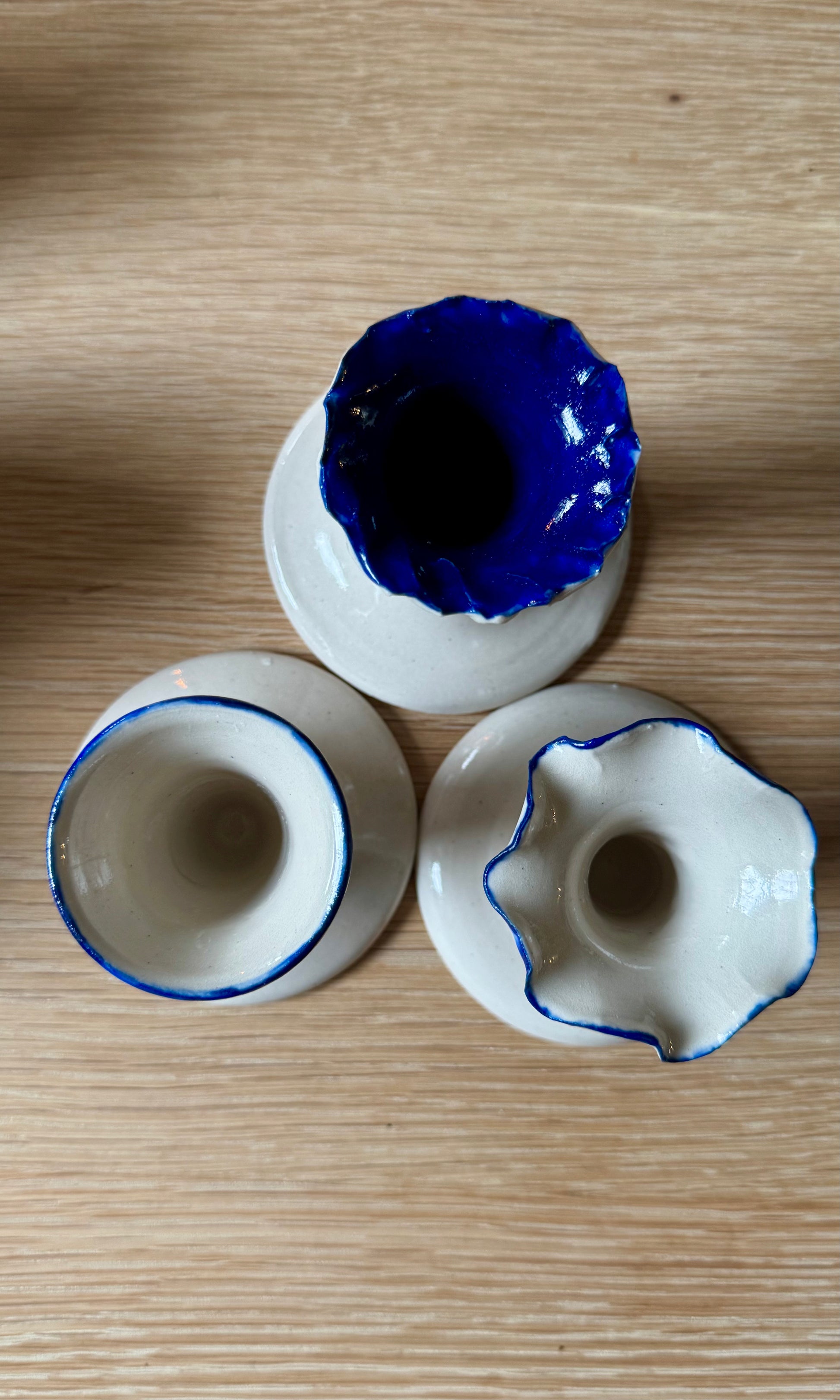 Three ceramic candle stick holders with blue rims on a wooden surface
