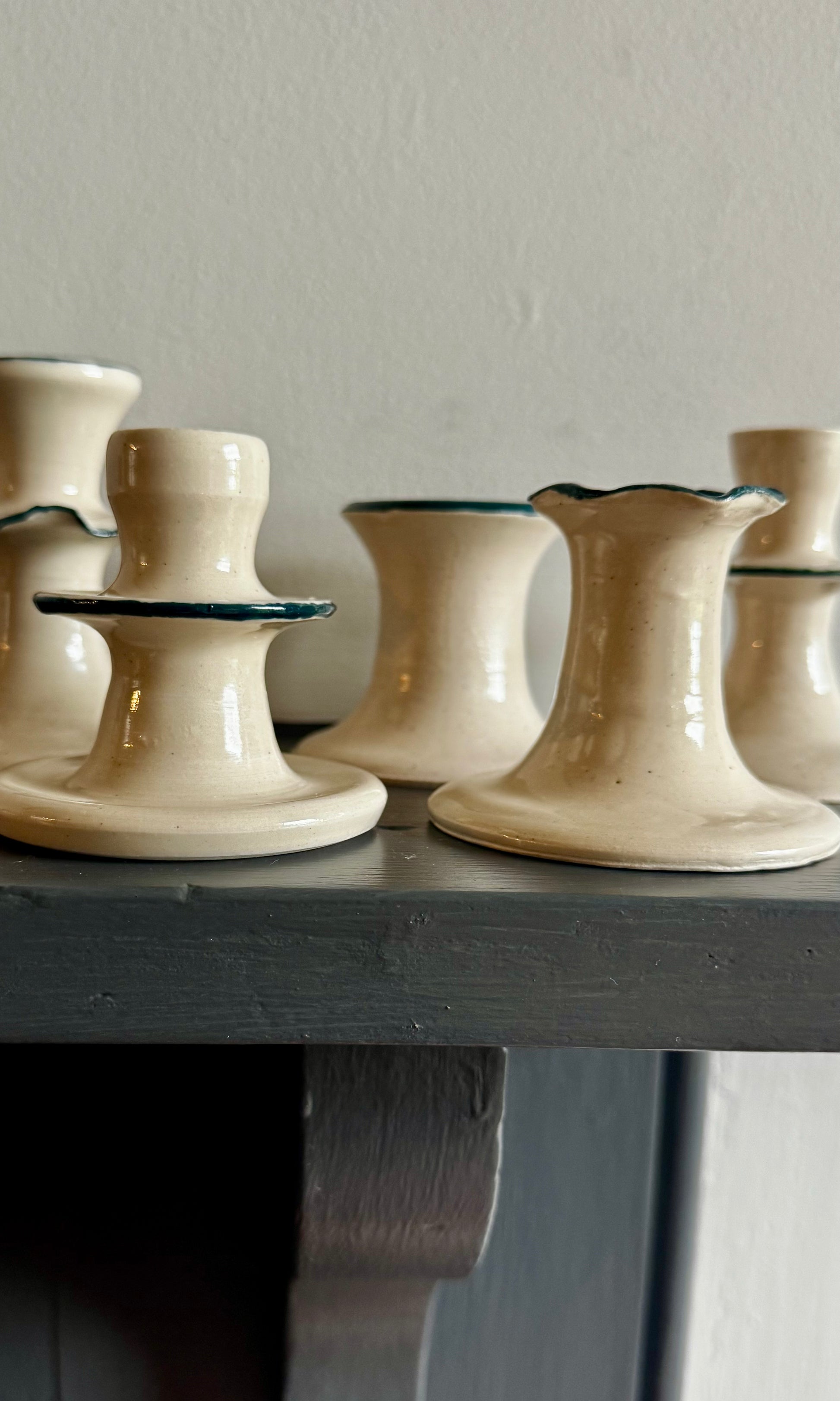 Set of ceramic mallard green and white candle holders on a wooden surface with a neutral background