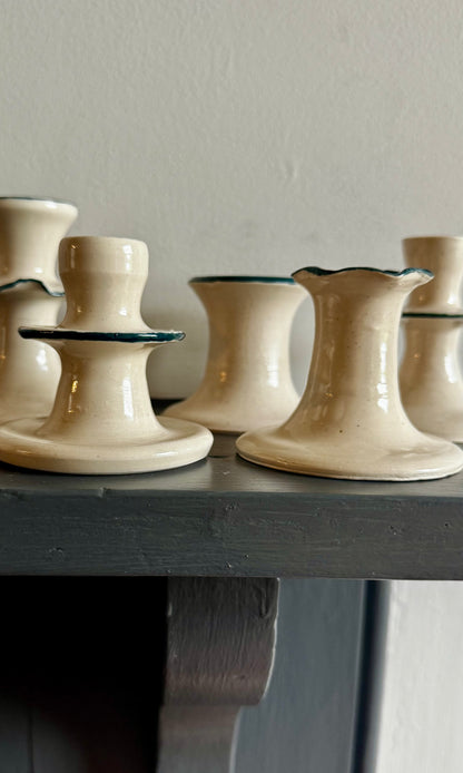 Set of ceramic mallard green and white candle holders on a wooden surface with a neutral background